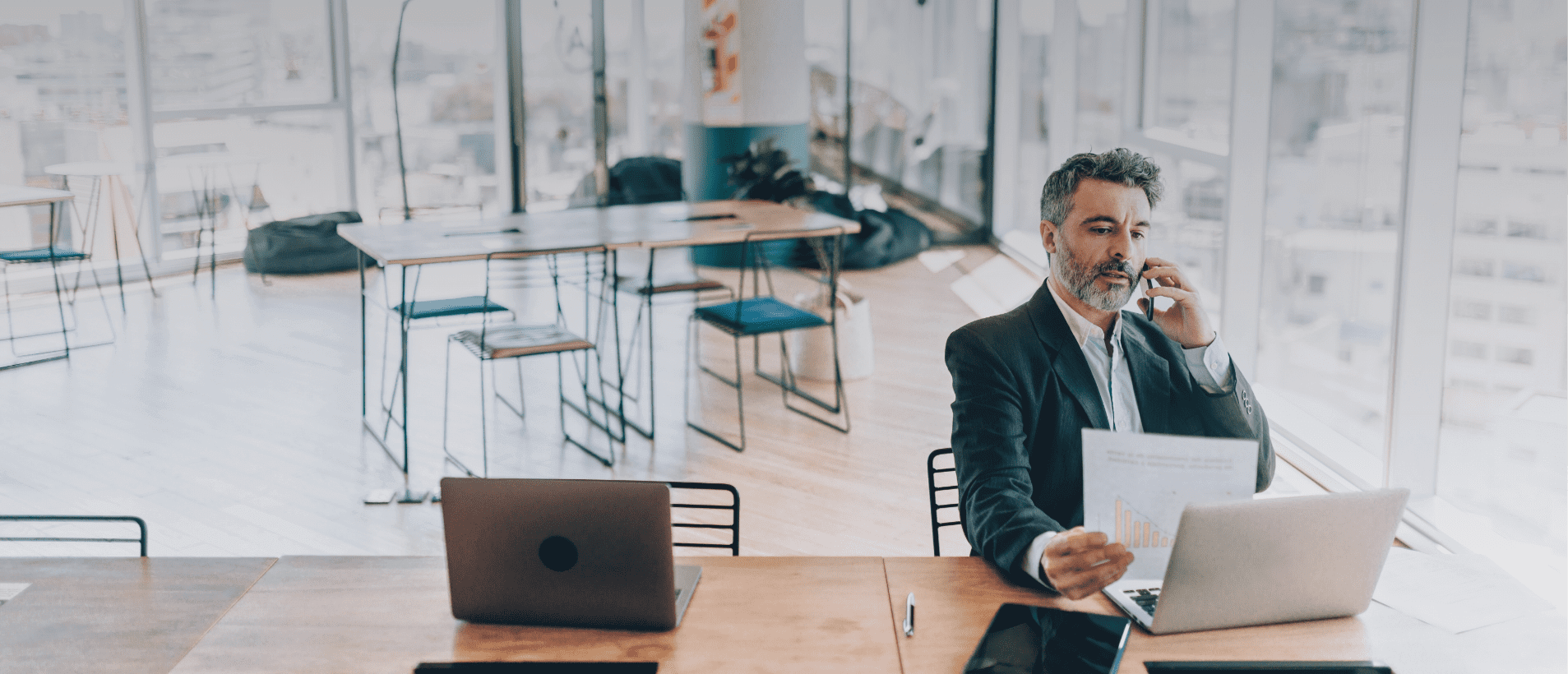 Man on the phone using a laptop and phone in a business setting