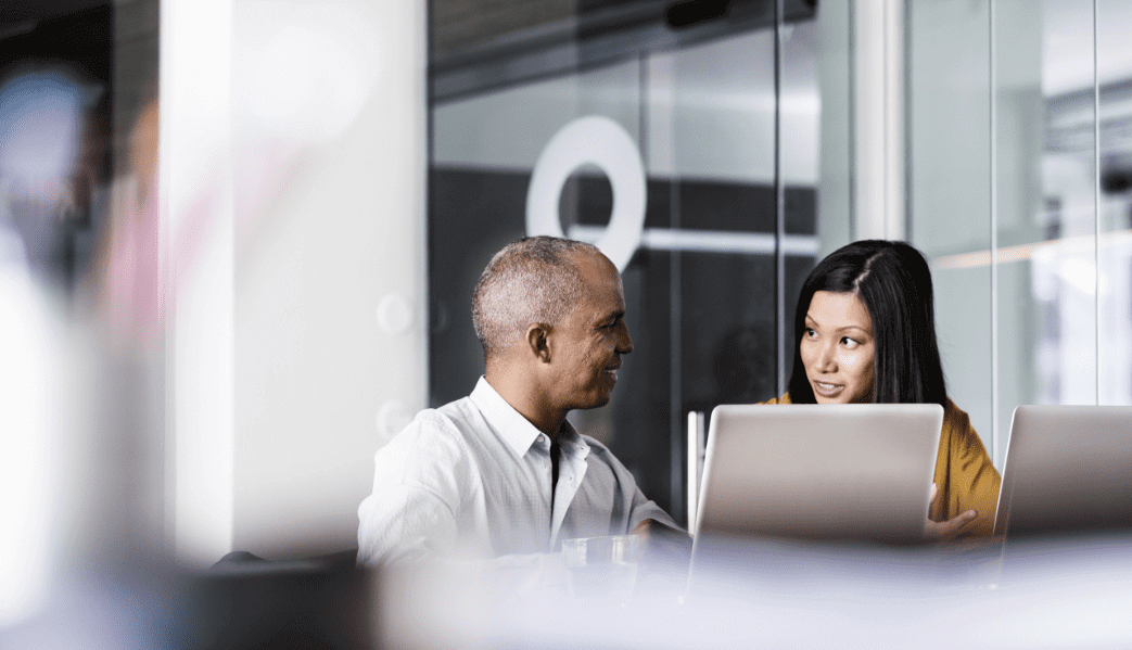 Man and woman talking to each other in front of computer screens