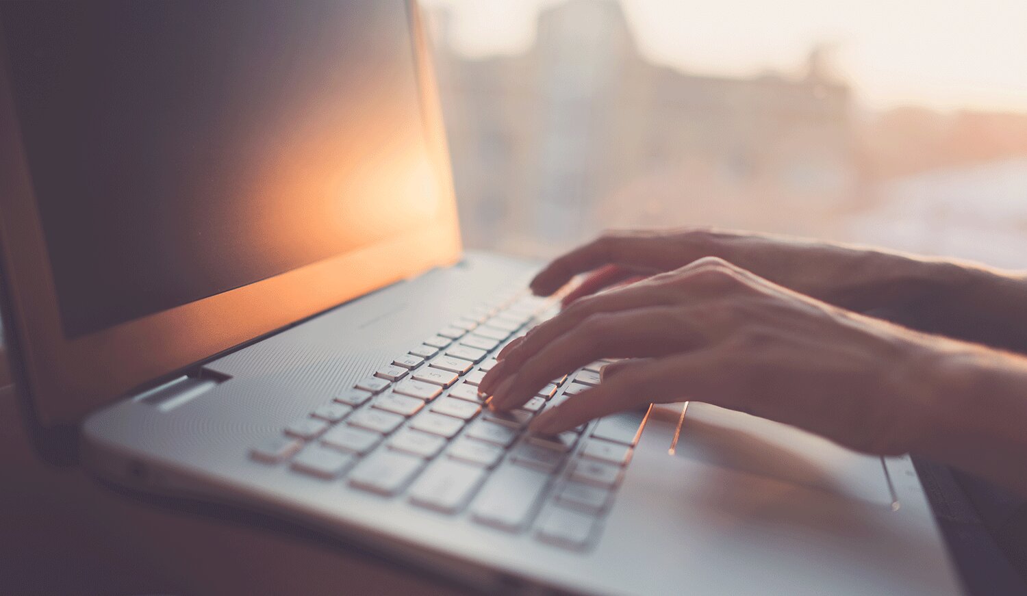 Hands typing on a laptop