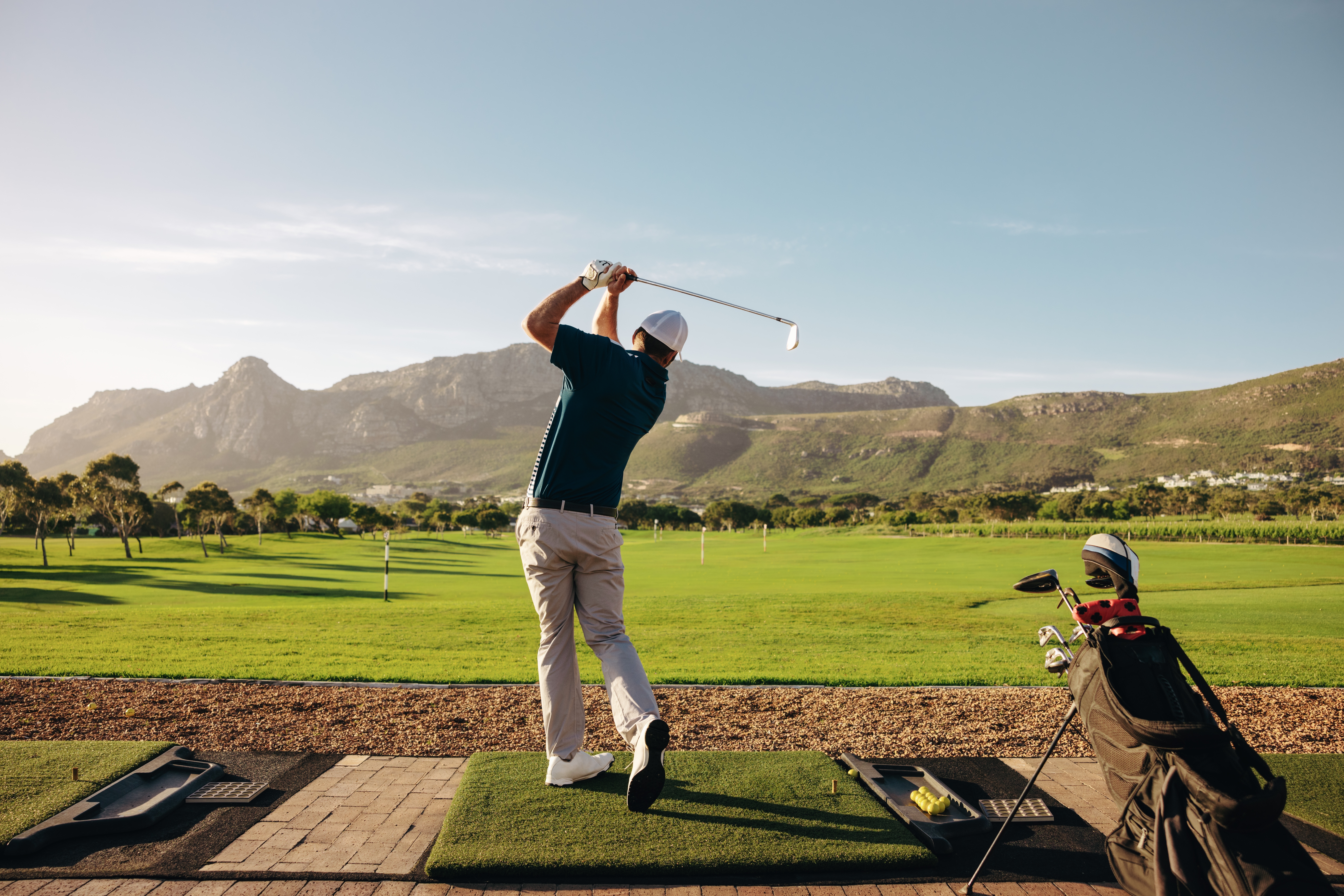 Man swinging a golf club on a golf course.